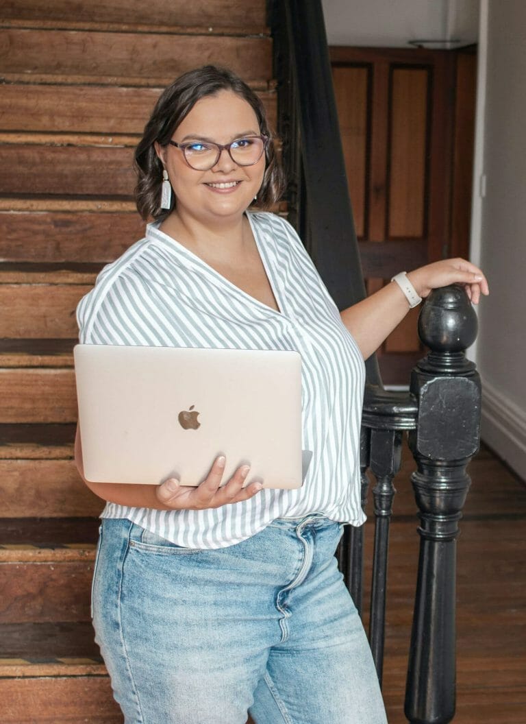 website developer standing holding a laptop and smiling to the camera